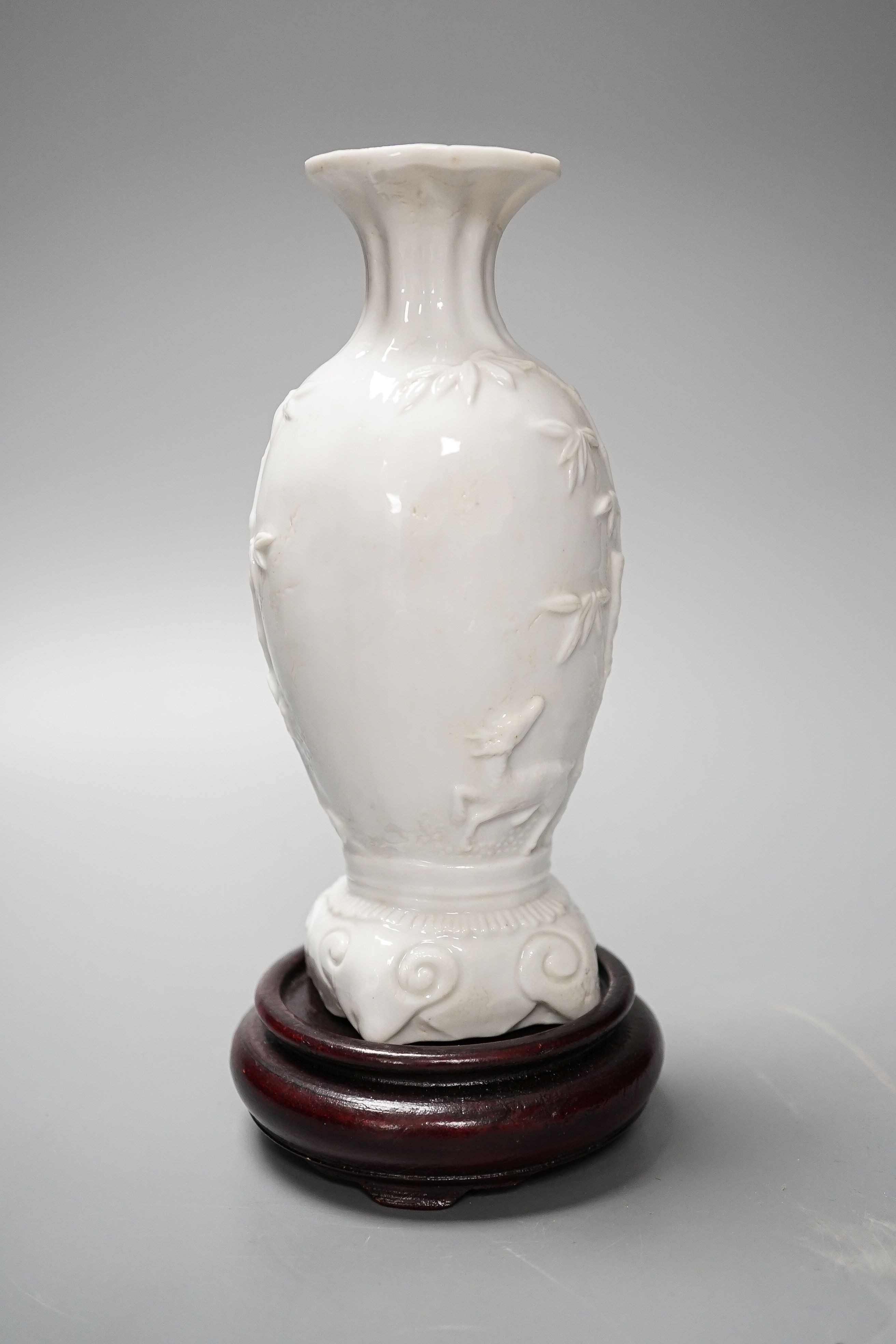 A Chinese 'deer and bamboo' moulded porcelain vase, 19th century, wood stand, height overall 20cm